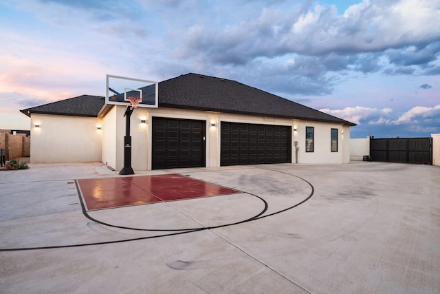 property exterior at dusk featuring stucco siding, driveway, and fence