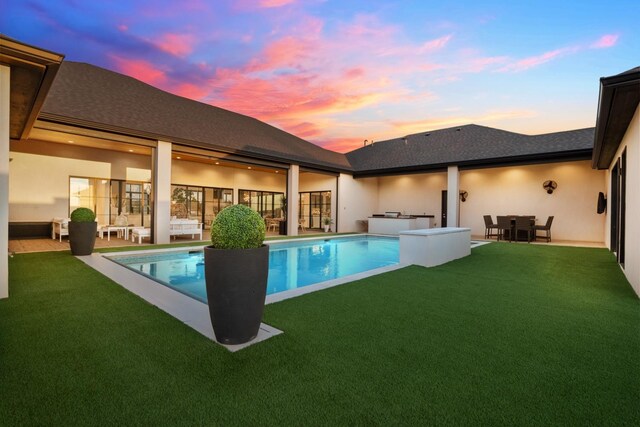 pool at dusk with a patio, area for grilling, and a yard