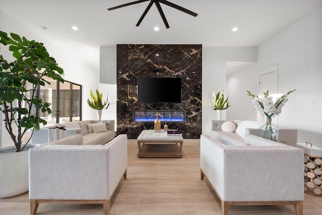 living room featuring a ceiling fan, wood finished floors, recessed lighting, and a premium fireplace