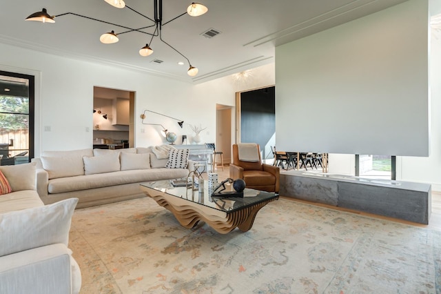 living room featuring a healthy amount of sunlight, ornamental molding, and a chandelier