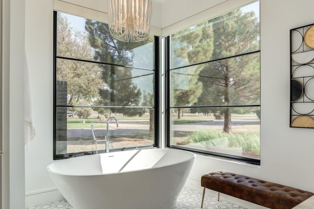 bathroom with plenty of natural light, a bath, and a chandelier