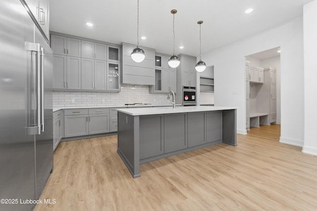 4806 139th St, Lubbock, TX 79424 - kitchen featuring stainless steel appliances, gray cabinets, light countertops, decorative backsplash, and a center island with sink