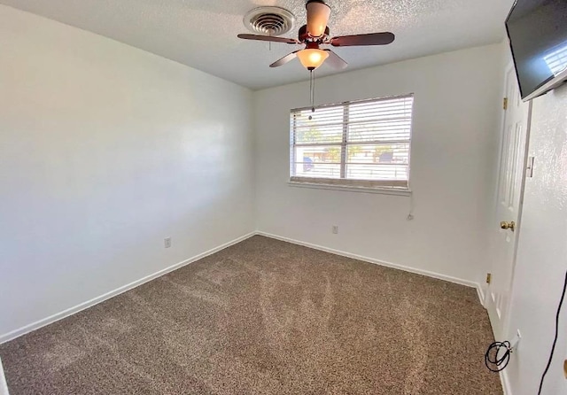 empty room featuring a textured ceiling, ceiling fan, and dark colored carpet