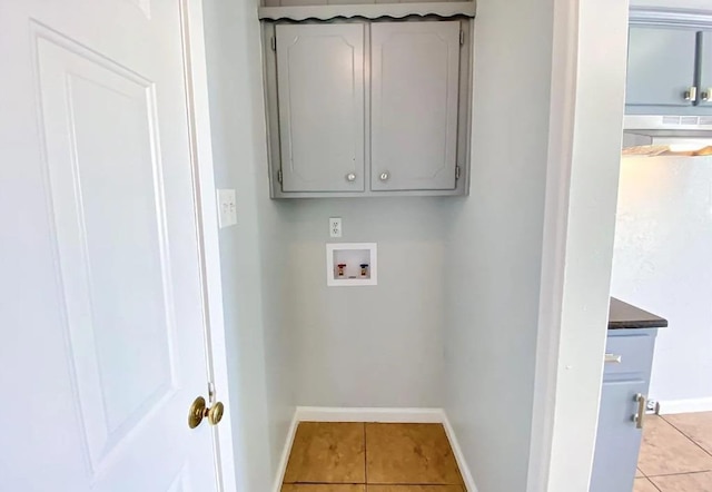 clothes washing area featuring light tile patterned floors, hookup for a washing machine, and cabinets