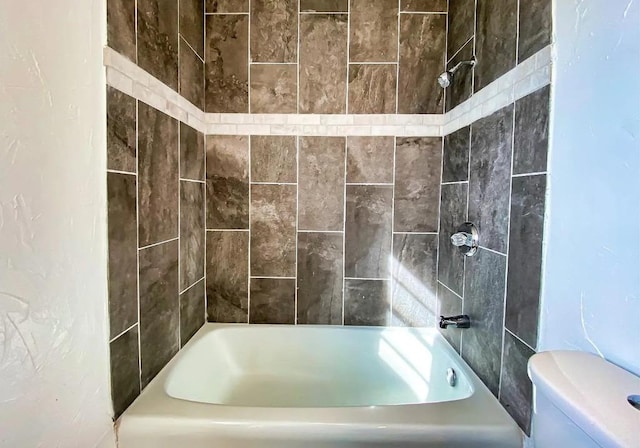 bathroom featuring tiled shower / bath and toilet