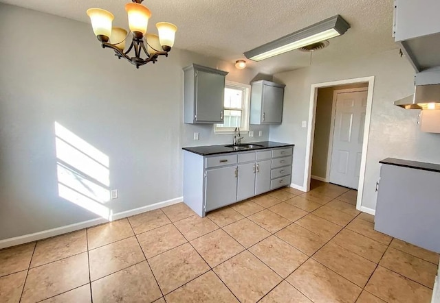 kitchen with sink, gray cabinets, an inviting chandelier, a textured ceiling, and light tile patterned flooring