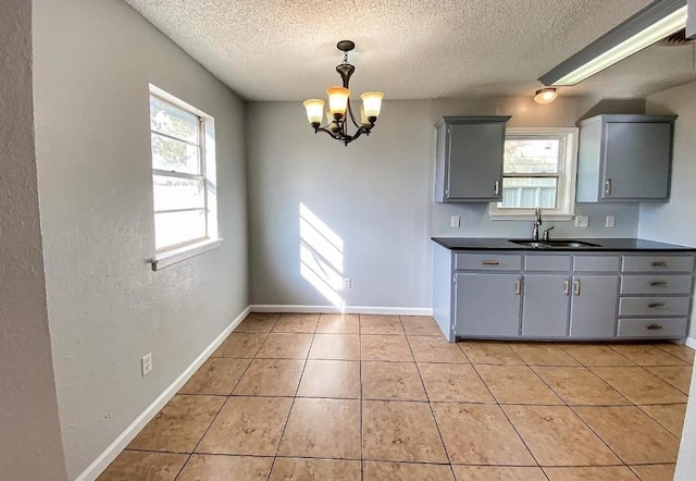 kitchen featuring light tile patterned flooring, sink, a textured ceiling, and gray cabinetry