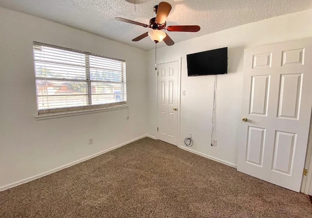 unfurnished bedroom featuring ceiling fan, a textured ceiling, and dark colored carpet