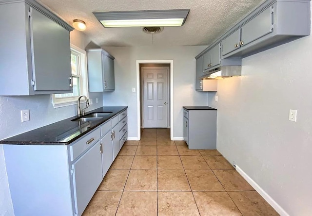 kitchen with gray cabinetry, sink, a textured ceiling, and light tile patterned floors