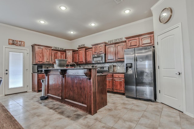 kitchen featuring appliances with stainless steel finishes, a kitchen island with sink, a breakfast bar, and decorative backsplash