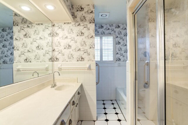 full bathroom featuring vanity, toilet, independent shower and bath, and tile walls