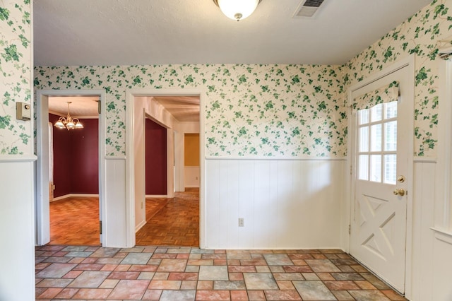 spare room with a textured ceiling and a chandelier