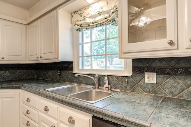 kitchen featuring tasteful backsplash, white cabinetry, sink, and tile countertops