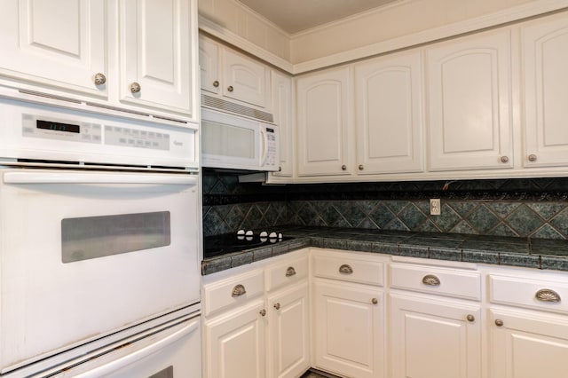 kitchen with white cabinetry, white appliances, and decorative backsplash