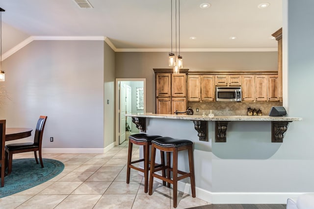 kitchen featuring crown molding, a kitchen bar, decorative light fixtures, and decorative backsplash