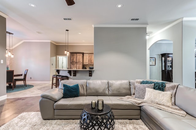 living room with crown molding, ceiling fan, and light hardwood / wood-style floors