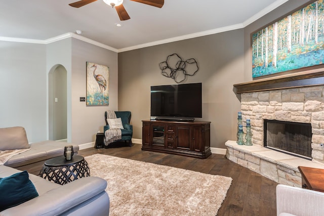 living room featuring ceiling fan, a fireplace, ornamental molding, and dark hardwood / wood-style flooring