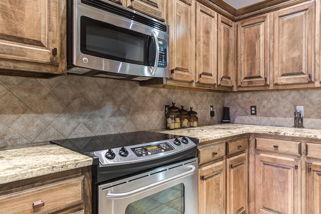 kitchen with light stone countertops, decorative backsplash, and stainless steel appliances