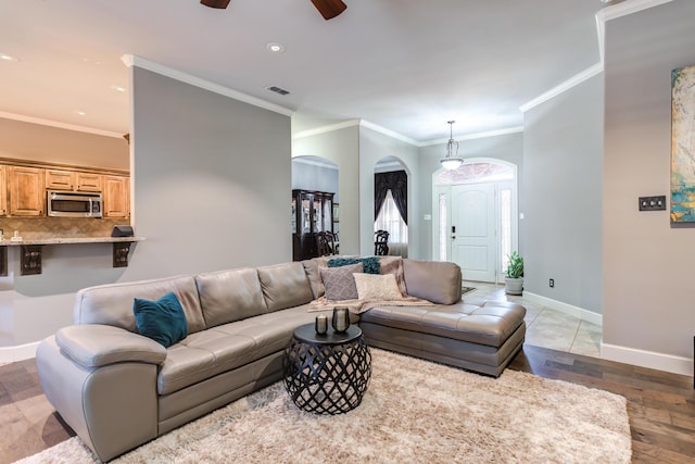 living room with wood-type flooring, ceiling fan, and crown molding