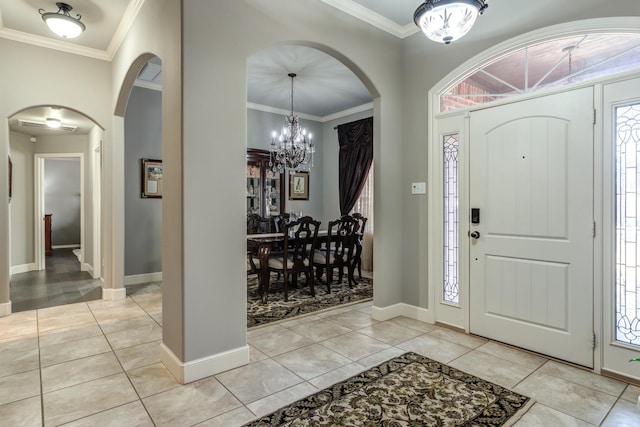 foyer entrance with crown molding, a healthy amount of sunlight, a chandelier, and light tile patterned floors