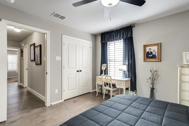 bedroom with hardwood / wood-style flooring, a closet, ceiling fan, and multiple windows