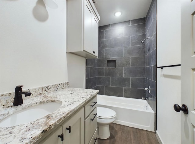 full bathroom with vanity, hardwood / wood-style flooring, toilet, and tiled shower / bath