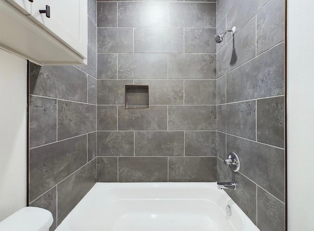 bathroom with tiled shower / bath combo and toilet