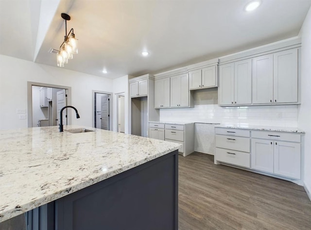 kitchen featuring light stone counters, sink, dark wood-type flooring, and hanging light fixtures