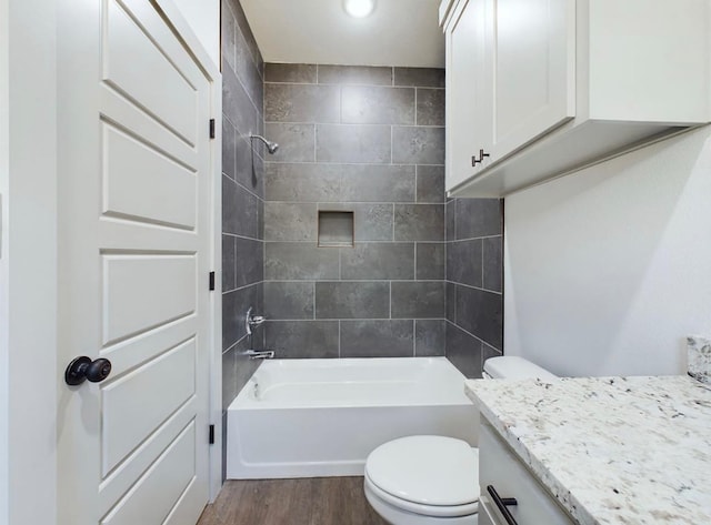 full bathroom with tiled shower / bath combo, vanity, wood-type flooring, and toilet