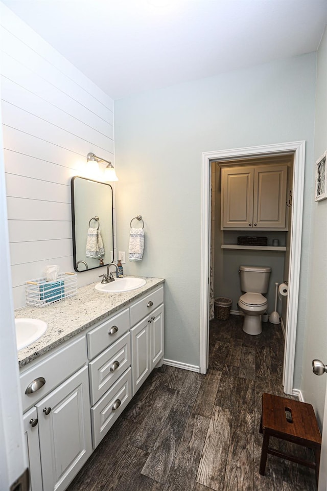 bathroom with hardwood / wood-style flooring, vanity, wooden walls, and toilet