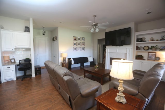 living room featuring ceiling fan, dark hardwood / wood-style floors, and built in desk