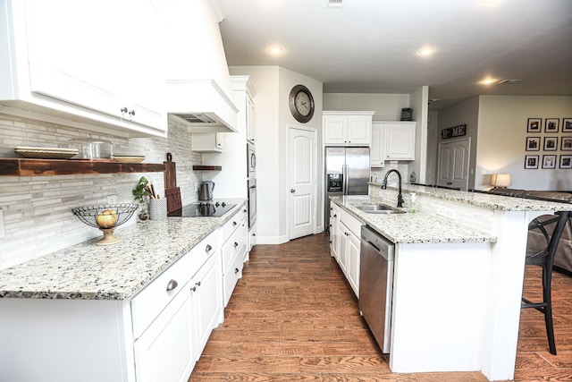 kitchen featuring appliances with stainless steel finishes, a breakfast bar, white cabinetry, sink, and custom range hood