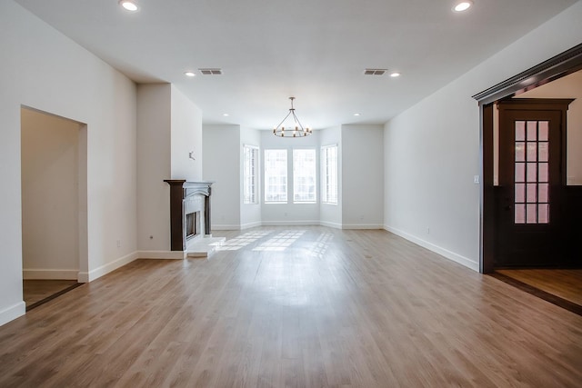 unfurnished living room with a notable chandelier and light wood-type flooring