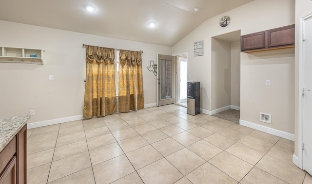 kitchen with vaulted ceiling, light stone countertops, and light tile patterned flooring