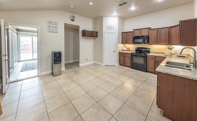 kitchen with light tile patterned flooring, sink, vaulted ceiling, light stone countertops, and black appliances