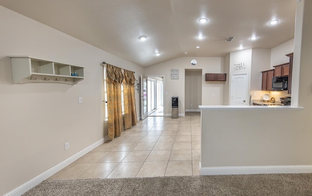 kitchen with lofted ceiling, light tile patterned floors, and kitchen peninsula