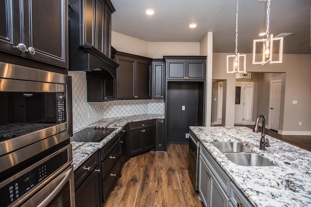 kitchen with black electric cooktop, light stone countertops, sink, and hanging light fixtures