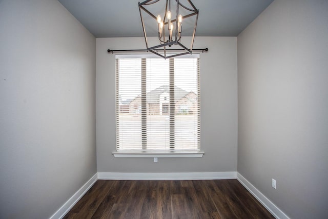 spare room featuring a notable chandelier and dark hardwood / wood-style flooring