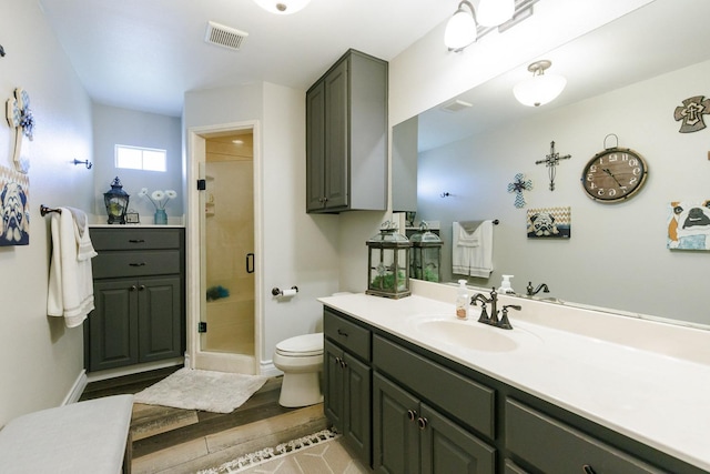 bathroom featuring visible vents, toilet, a stall shower, wood finished floors, and vanity