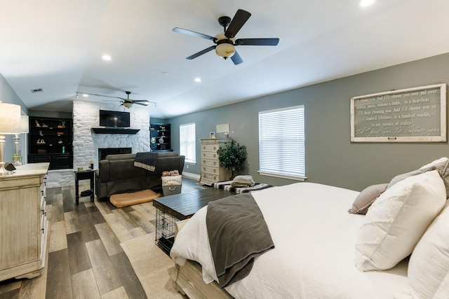 bedroom with visible vents, recessed lighting, a stone fireplace, dark wood-style flooring, and vaulted ceiling