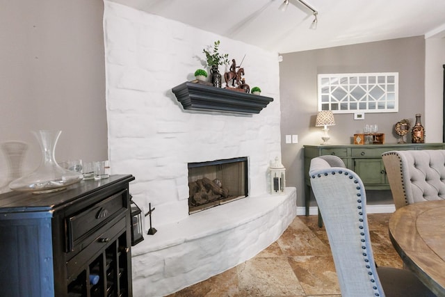 interior space featuring a bar, track lighting, a fireplace, and stone finish floor