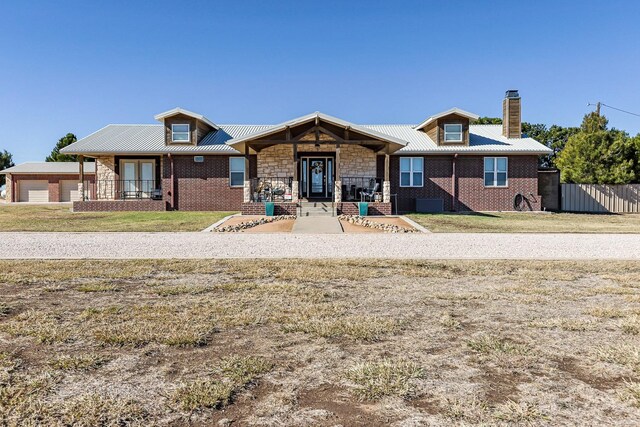 view of front of house featuring a front lawn, brick siding, stone siding, and metal roof