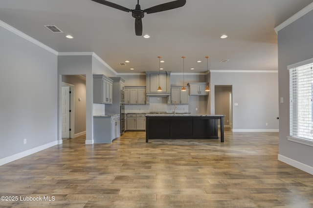 4020 125th St, Lubbock, TX 79423 - kitchen featuring gray cabinetry, ceiling fan, decorative backsplash, a kitchen island with sink, and hanging light fixtures