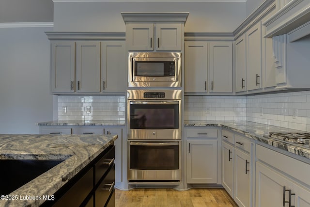 4020 125th St, Lubbock, TX 79423 - kitchen featuring appliances with stainless steel finishes, gray cabinets, decorative backsplash, stone countertops, and light wood-style flooring