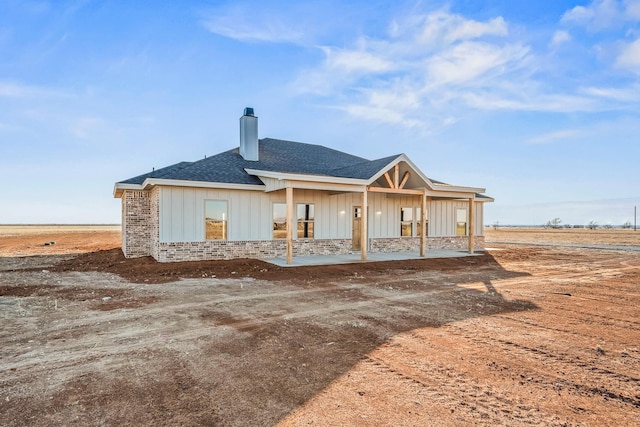 back of property featuring covered porch and a rural view