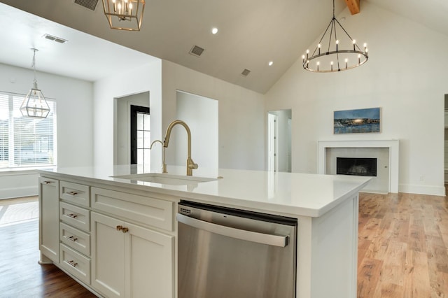 kitchen featuring sink, dishwasher, a kitchen island with sink, hanging light fixtures, and white cabinets