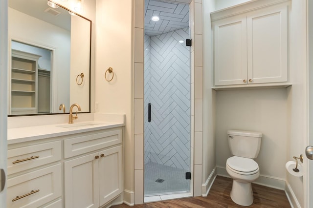 bathroom featuring vanity, hardwood / wood-style floors, a shower with shower door, and toilet