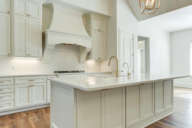 kitchen featuring an island with sink, premium range hood, gas cooktop, and light hardwood / wood-style flooring