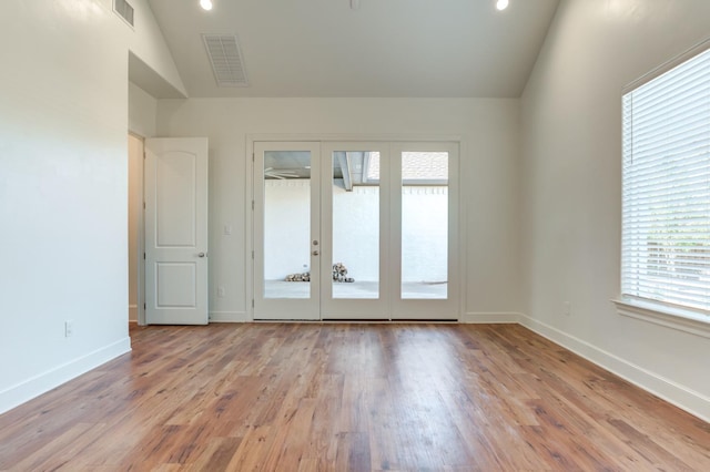 empty room with french doors, lofted ceiling, and light hardwood / wood-style flooring