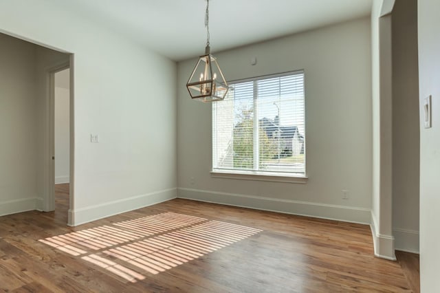 spare room featuring hardwood / wood-style flooring and a chandelier